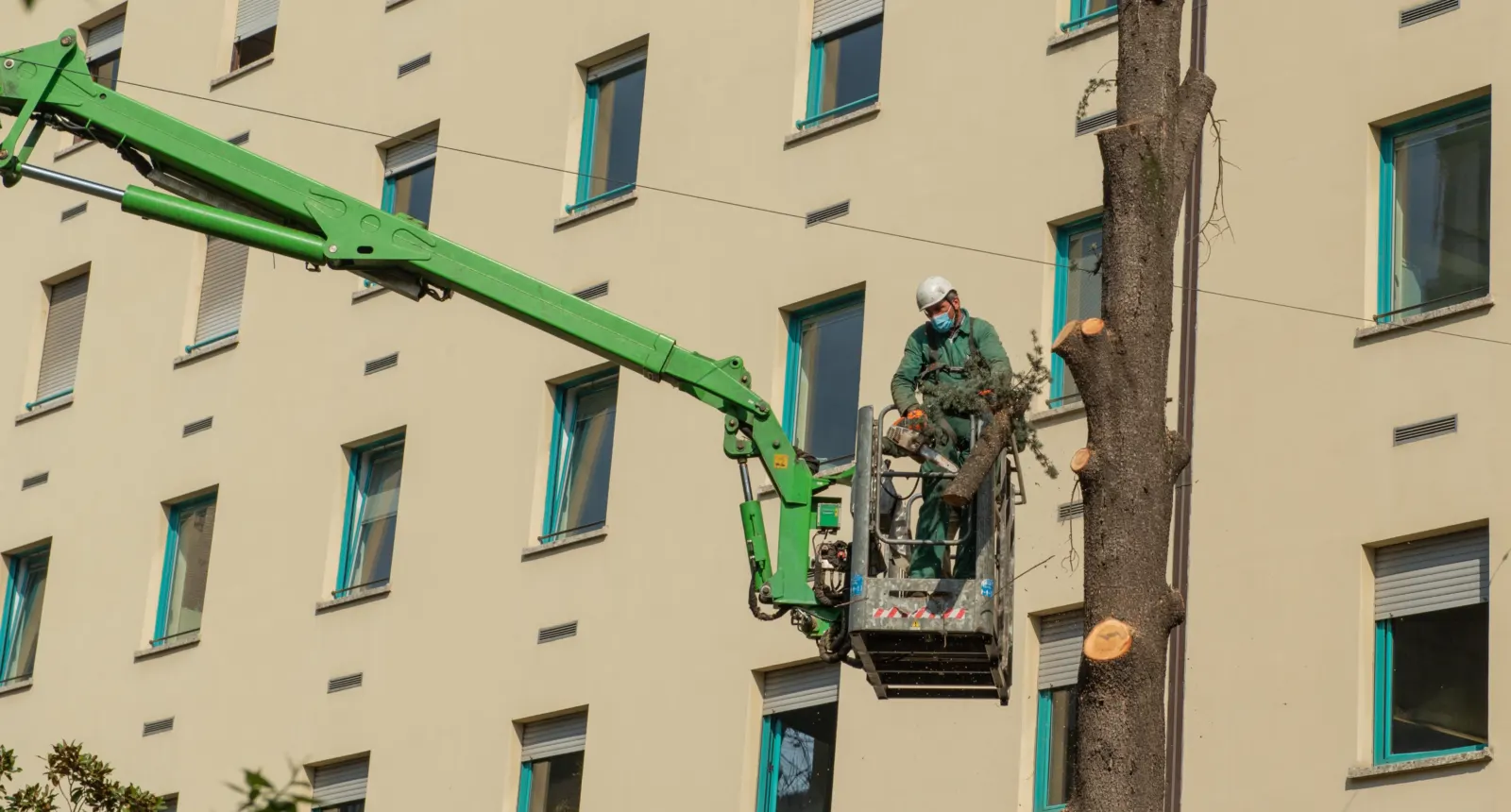 Bucket truck working beside a tall building during a tree removal